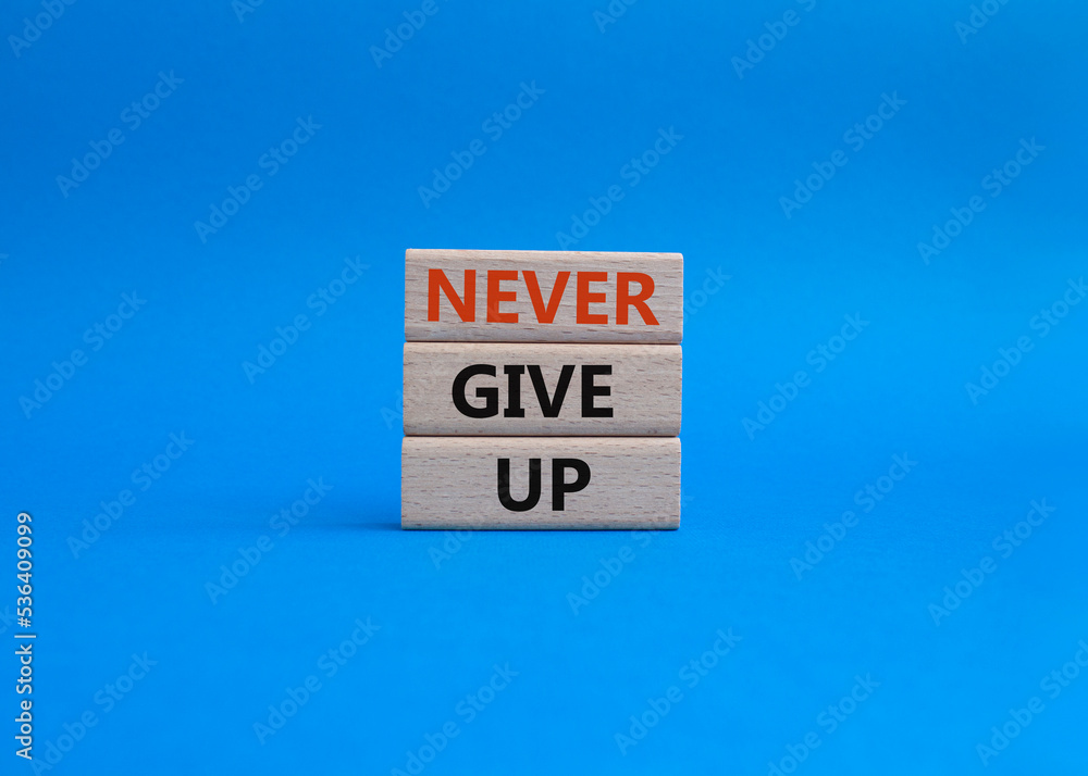 Never give up symbol. Concept words Never give up on wooden blocks. Beautiful blue background. Business and Never give up concept. Copy space. Never give up symbol. Concept words Never give up on wooden blocks. Beautiful blue background. Business and Never give up concept. Copy space.