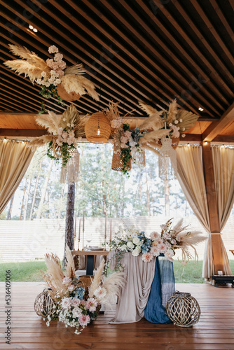 Wedding Decor. Festive table decorated with flowers on the center, candles, silverware and plates with silk napkins on dusty blue tablecloth