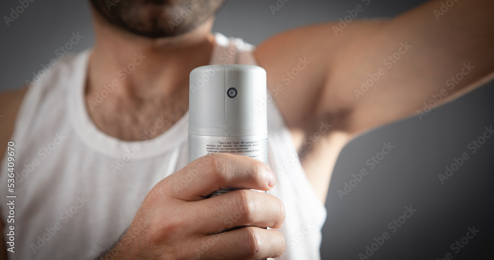 Young man holding bottle of deodorant. Young man holding bottle of deodorant.