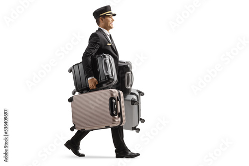 Slika na platnu Full length profile shot of a bellboy walking and carrying many suitcases