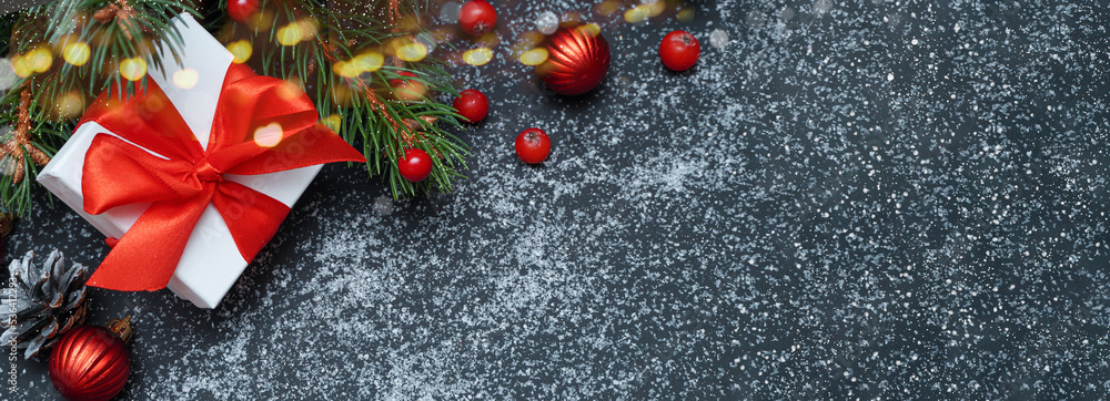 Spruce, fir branches, red berries, gift box on black background. Frame border. Christmas composition. Space for text. Banner. Spruce, fir branches, red berries, gift box on black background. Frame border. Christmas composition. Space for text. Banner.