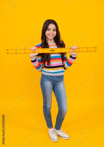 Teenager child school girl holding measure for geometry lesson. Measuring height. Measuring equipment. Kid student study math. Happy positive and smiling schoolgirl. © Olena