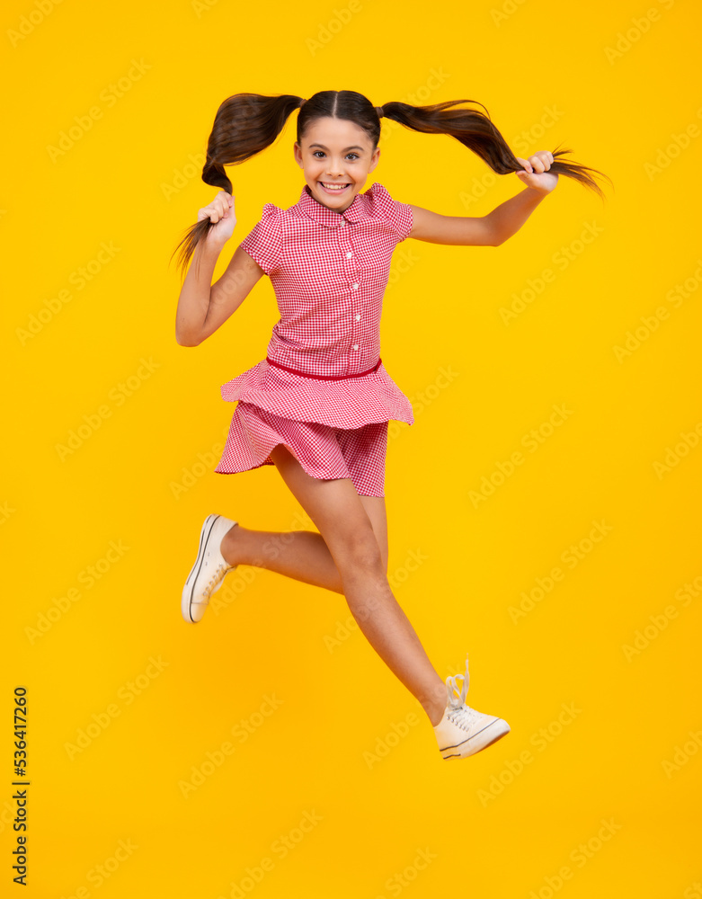 Excited teenager. Full length funny teenager kid jump enjoy rejoice win isolated on yellow background. Small child girl in dress jumping. Excited teenager. Full length funny teenager kid jump enjoy rejoice win isolated on yellow background. Small child girl in dress jumping.