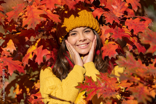 Child girl on autumn fall background, autumn kids face. cheerful girl in hat at fall leaves on natural background