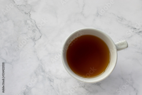 Cup of tea on table. Green herbal tea in mug on white marble background. Top view, copy space. Traditional teatime 