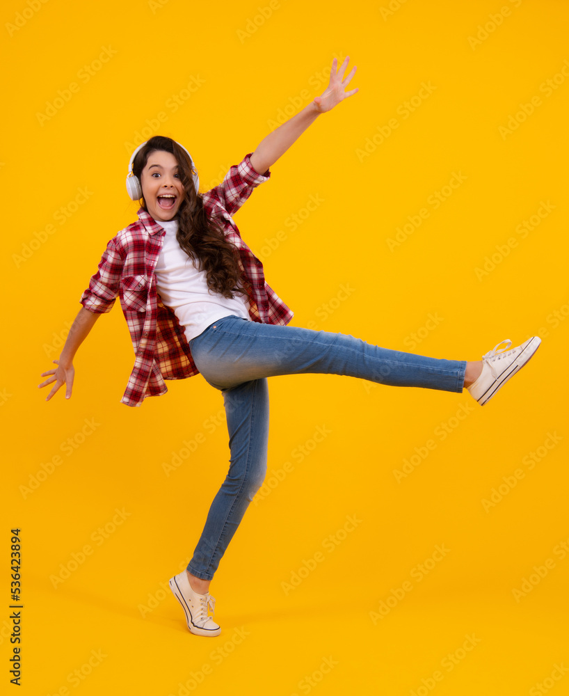 Amazed teenager. Child music concept. Teenager child girl dances in rhythm of melody, listens song in headphones. Child listening to music through earphones. Urban kids style, stylish hipster teen. Amazed teenager. Child music concept. Teenager child girl dances in rhythm of melody, listens song in headphones. Child listening to music through earphones. Urban kids style, stylish hipster teen.
