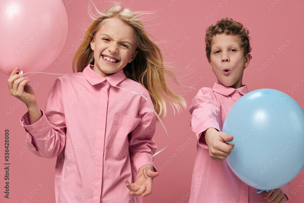 funny, funny children stand playing with balloons and have fun standing on a pink background funny, funny children stand playing with balloons and have fun standing on a pink background