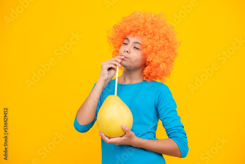 Summer fruits. Teenager child girl hold citrus fruit pummelo or pomelo  isolated on yellow background. Kid healthy eating.