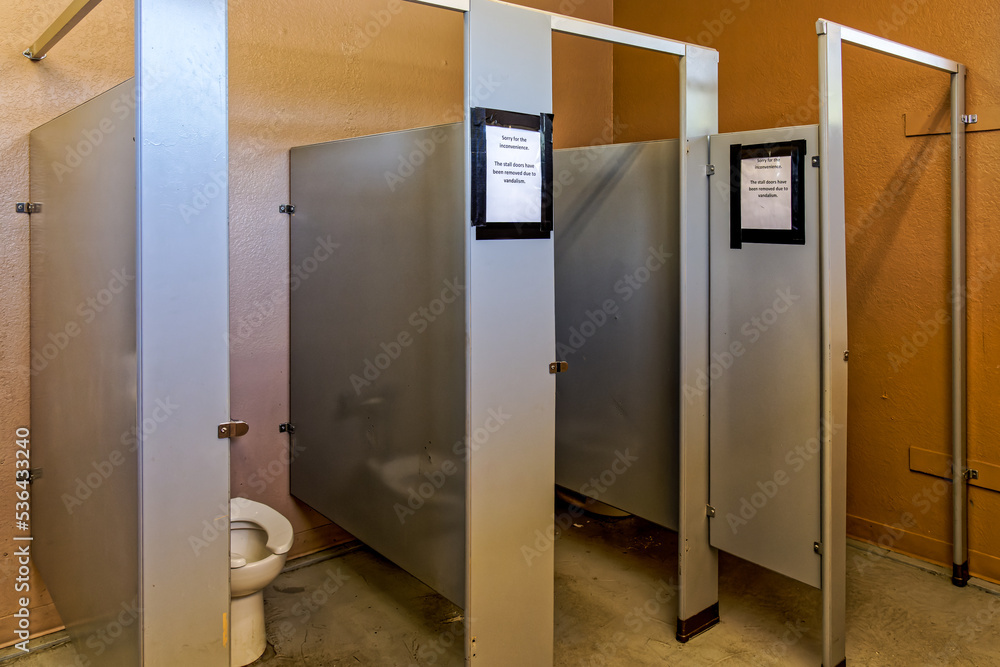 Womens restroom with stall doors removed. Sign says Sorry for the inconvenience.. The stall doors have been rmoved due to vandalism Womens restroom with stall doors removed. Sign says Sorry for the inconvenience.. The stall doors have been rmoved due to vandalism