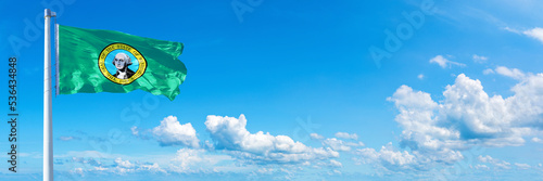 Washington - state of USA, flag waving on a blue sky in beautiful clouds - Horizontal banner photo