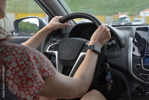 a girl in a dress driving a car. a view from the car interior of a girl driving a car with her hands on the steering wheel of a car.