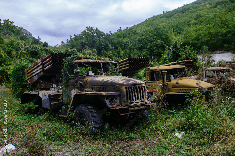 Old abandoned rusty military trucks overgrown by plants