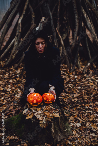 Woman  fashion girl in witch costume and pumpkin. Halloween decor with carved pumpkins. Halloween look  outfit. Halloween decoration with pumpkins. Pumpkin head