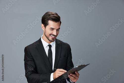 Portrait of a business man in a stylish suit smile with teeth hands up handsome face on gray isolated background with tablet in hand. Business concept young businessman startup copy space.