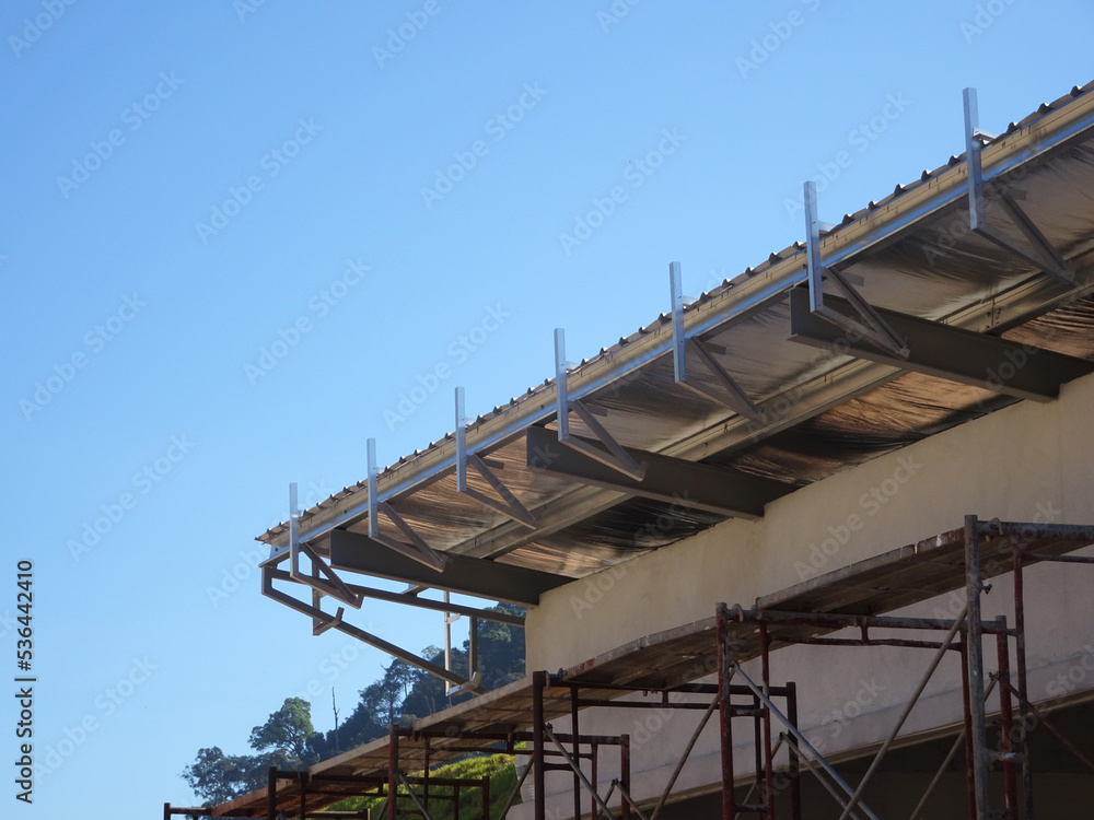 Naklejka premium MELAKA, MALAYSIA - SEPTEMBER 16, 2022: Installation of the aluminum cladding frame at the end of the roof is underway. The metal decking roof system is equipped with a heat-resistant silsalation layer
