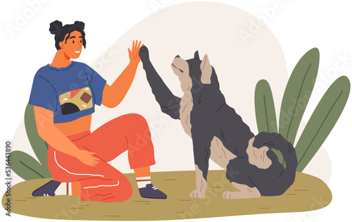 Female pet owner plays with dog. Caring for four-footed friend concept. Happy lady with puppy, domestic animal, human companion at home. Dog follows command, gives paw to woman. Girl training doggy