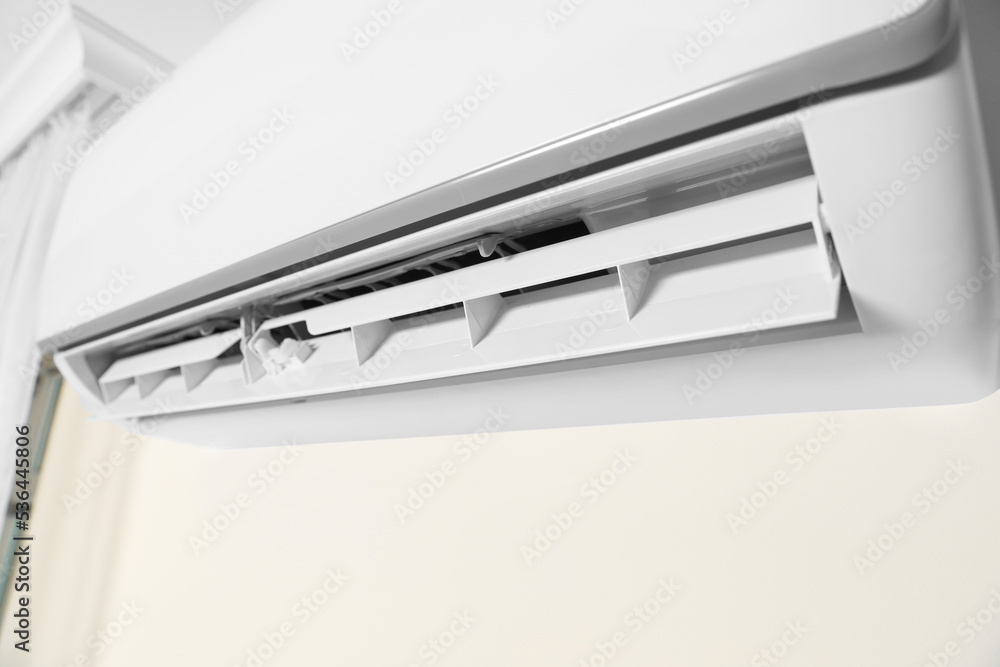 Modern air conditioner on white wall indoors, closeup view Modern air conditioner on white wall indoors, closeup view