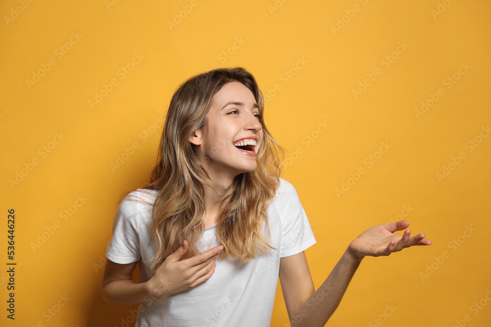 Cheerful young woman laughing on yellow background Cheerful young woman laughing on yellow background