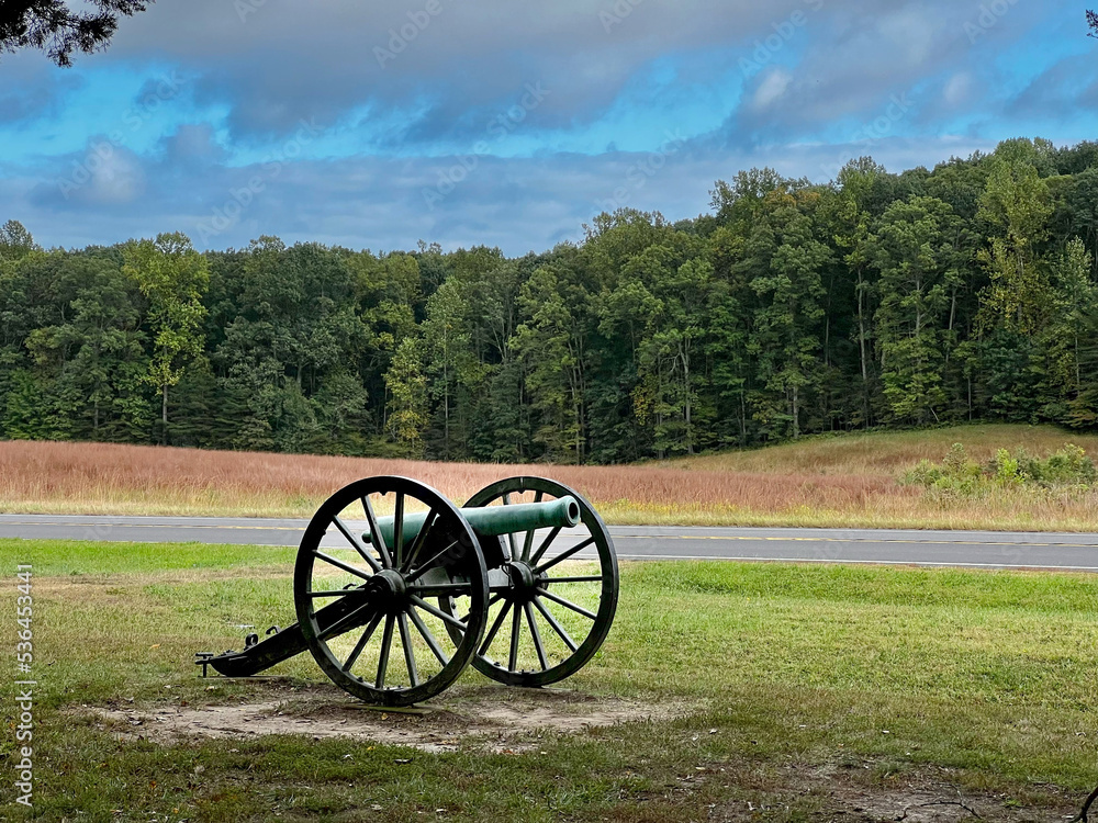 Civil War era cannon in green field with dramatic blue sky