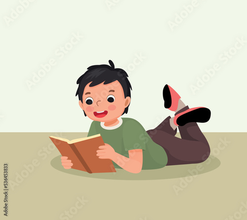Cute little boy reading book lying on floor