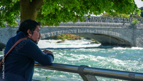 Joven adulto hispano posando cerca de un rio en un dia soleado. Parque natural de Niagara Falls 