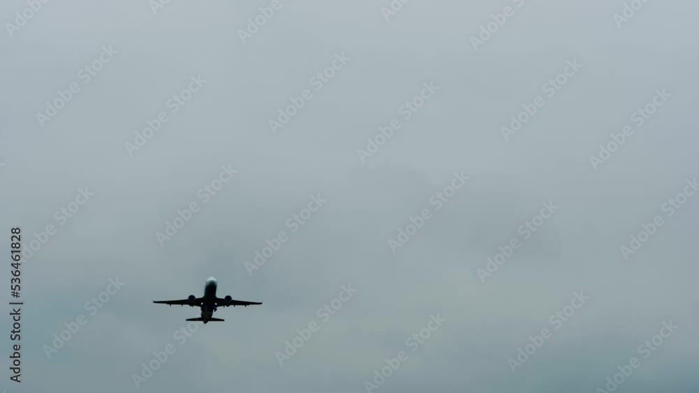 Slow motion: silhouette of large passenger airplane, airliner is flying in the dramatic overcast, grey sky. Transportation, departing, dark, mystery, gloomy and flight concept Slow motion: silhouette of large passenger airplane, airliner is flying in the dramatic overcast, grey sky. Transportation, departing, dark, mystery, gloomy and flight concept