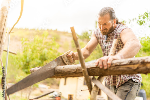 Man making an effort to cut a log