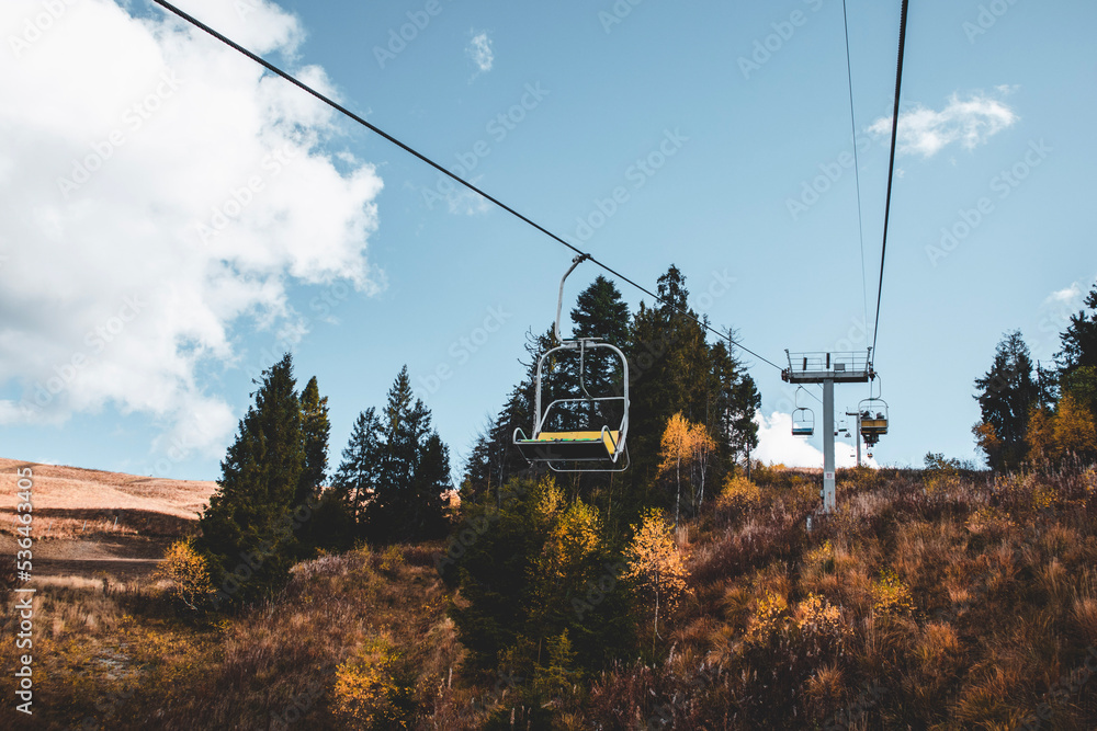 Ski chair-lift in front of blue sky in sunny day. No people. Elevator in autumn