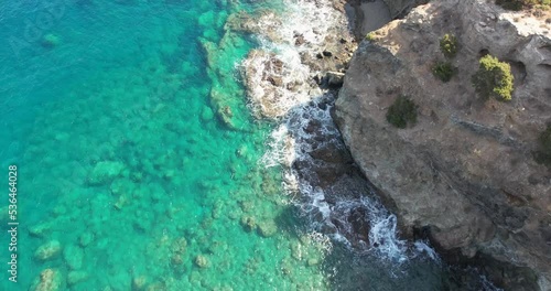drone footage. We see the sea collide with the stones and sand of a beach