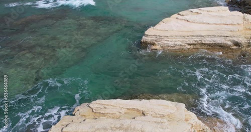 Establishing shot of waves crashing against cliffs in summer