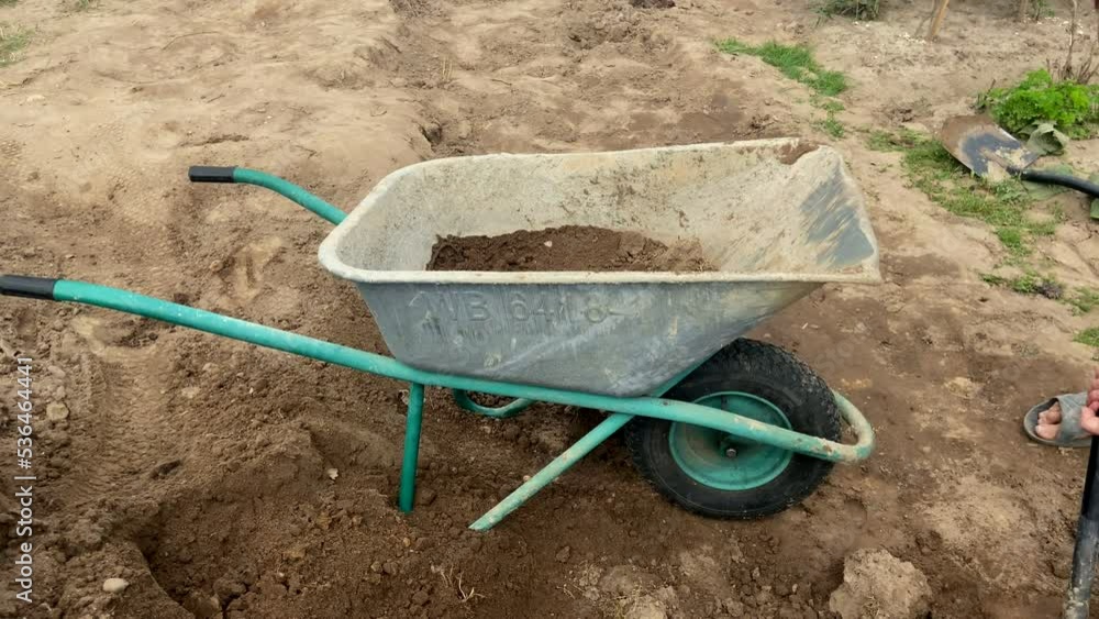 Video „Wheelbarrow with ground on gardering. Loading soil into a