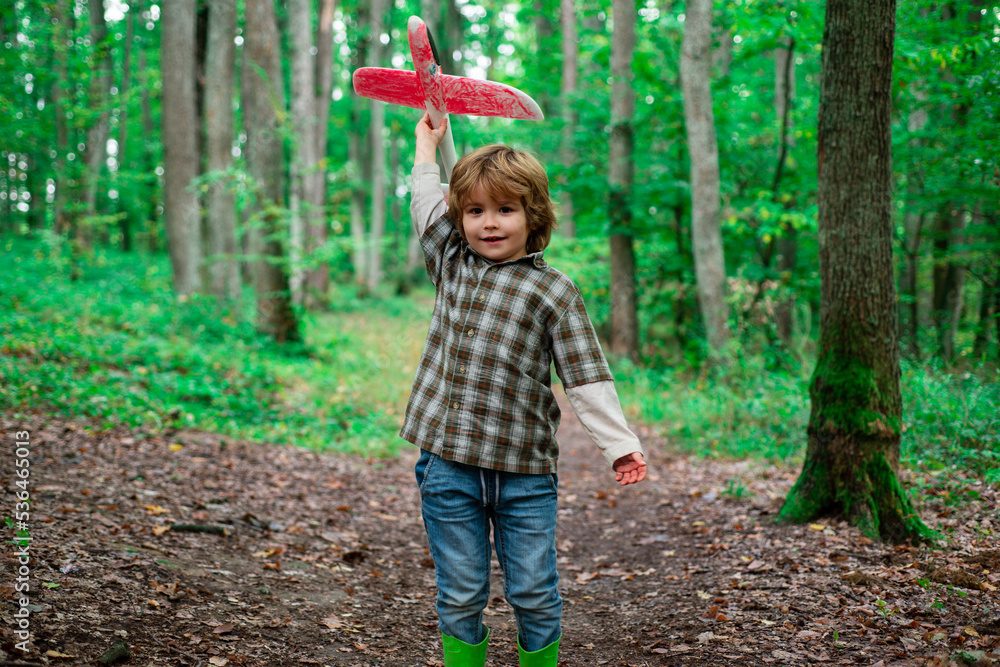 Kid dreaming and plays with a toy plane in the park. Dreams of travel. Development, growth, dreams and plans. Imagination and dream concept. Kid dreaming and plays with a toy plane in the park. Dreams of travel. Development, growth, dreams and plans. Imagination and dream concept.
