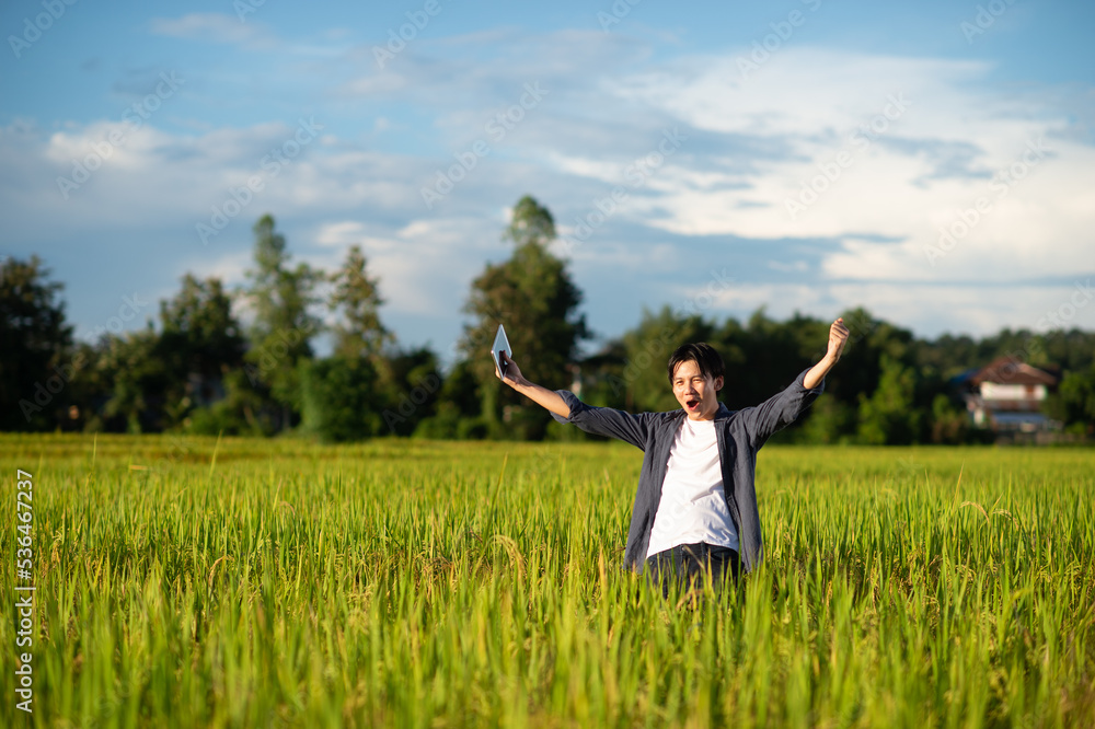 Beautiful dramatic portrait of asian man rural happy farmer standing in the rice field , in a day time summer. Pleased farmer is happily enjoying flourished agricultural crops. Beautiful dramatic portrait of asian man rural happy farmer standing in the rice field , in a day time summer. Pleased farmer is happily enjoying flourished agricultural crops.