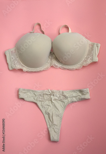 Details and close-up shot of the modern classic sexy beige seamless smooth luxury elegant women push up bra set on pink background. 