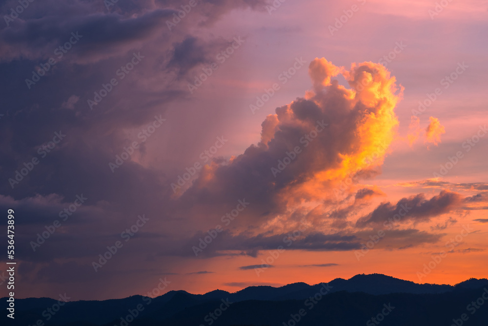 Cumulonimbus cloud and rain fall over the mountain during sunset sky with golden light