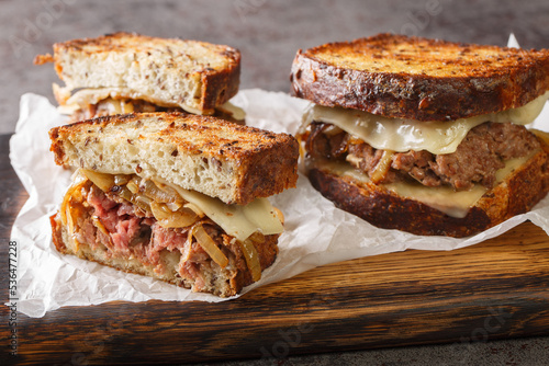 Canvas Print classic beef patty melt sandwich using crispy rye bread, cheese, and tender onions closeup on the wooden board on the table