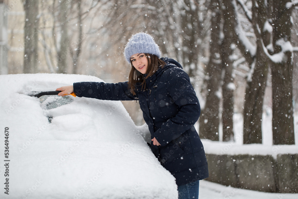 Woman removing snow from car windshield Woman removing snow from car windshield