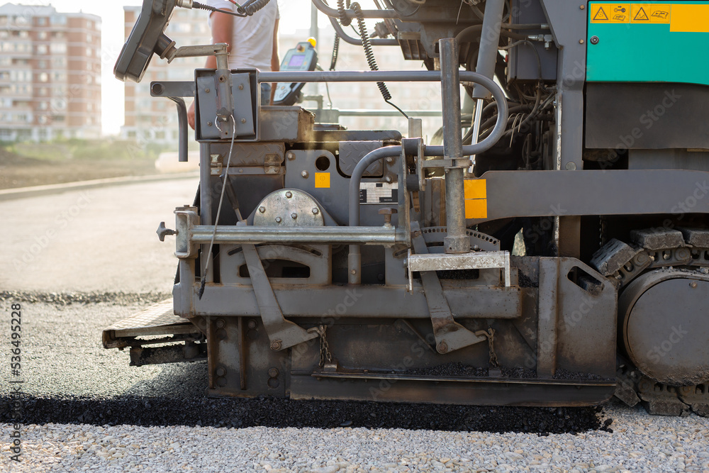 An asphalt spreader or an asphalt paver machine on a road construction site. Road repairs.