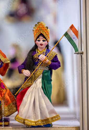 Handmade colorful Bharat mata doll of jute holding Indian national flag with blurred background. selective focus on idol.