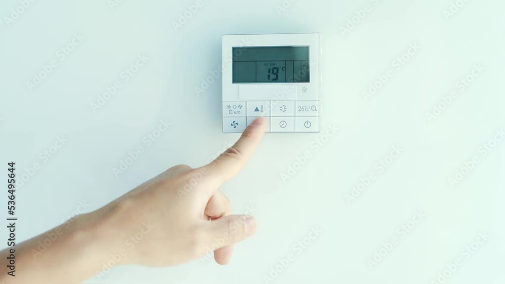 Closeup the man hand controls and presses the buttons The air conditioning and heating control panel for the apartment and office is located on a white wall. Close up Closeup the man hand controls and presses the buttons The air conditioning and heating control panel for the apartment and office is located on a white wall. Close up