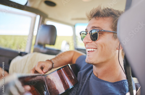 Music, guitar and young man in car on a roadtrip adventure in nature. Summer, holiday and journey on the road, fun musician on vacation. Travel, freedom and explore nature with musical instrument