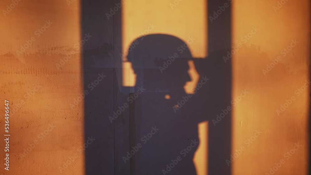 builder shadow falls on the wall silhouette. business building concept. worker in a helmet silhouette shadow falls on the wall with plaster idea concept. contractor in a helmet makes home repairs