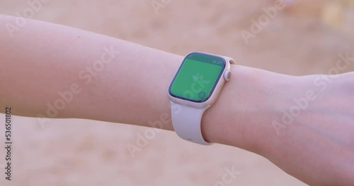 Woman using her smartwatch touchscreen with greenscreen. 