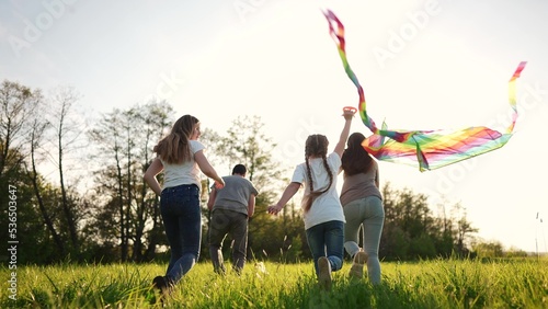 happy family. big family running with a kite. people in the park children child running together in the park at sunset silhouette. mom dad daughter and son are running. concept dream. fun kids run