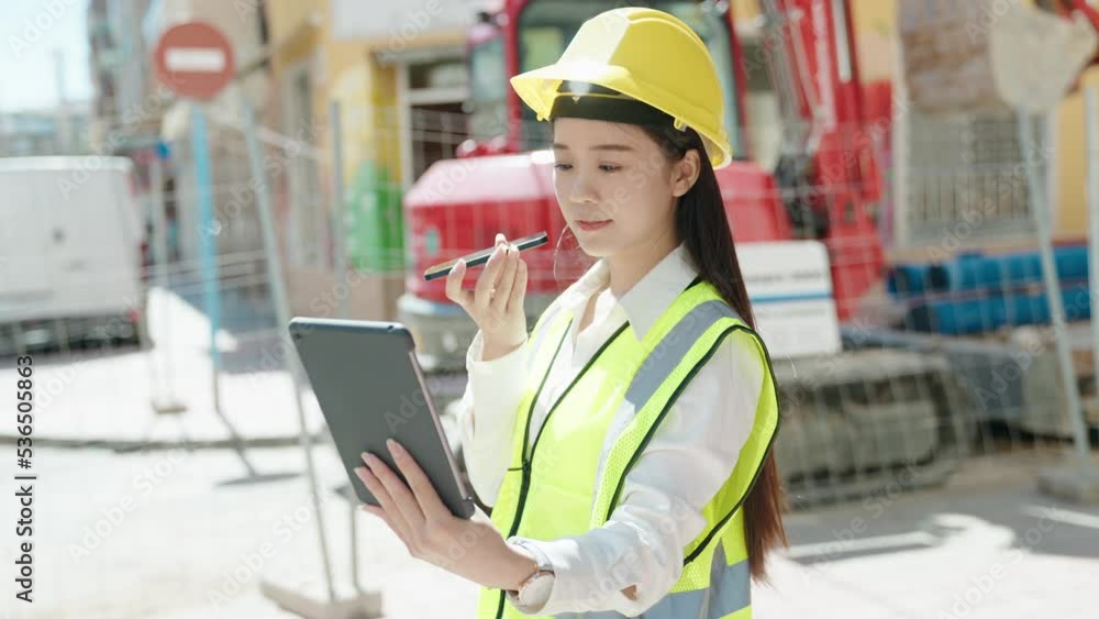 Young chinese woman architect talking on smartphone using touchpad at street Young chinese woman architect talking on smartphone using touchpad at street