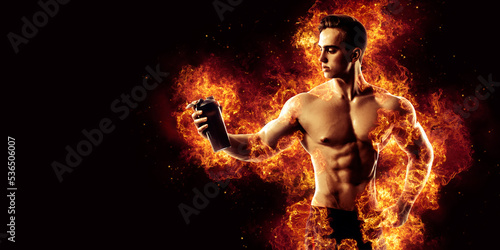 Muscular man with protein drink in shaker over dark background with fire flames © zamuruev