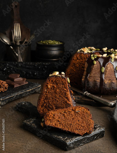 A piece of chocolate pumpkin cupcake with chocolate icing on a dark background