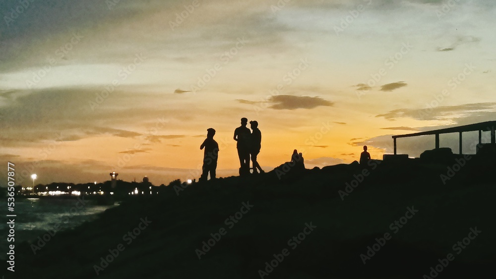 Obraz premium silhouettes of people on the beach at sunset