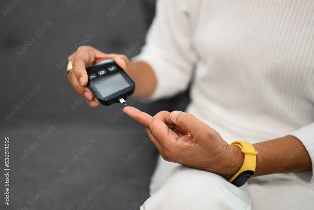 Mature diabetic woman using glucose meter on finger, measuring blood glucose. Diabetes and health care concept Mature diabetic woman using glucose meter on finger, measuring blood glucose. Diabetes and health care concept