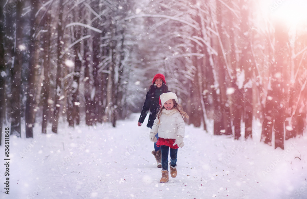 A winter fairy tale, a young mother and her daughter ride a sled in the forest. A girl on a sled with gifts on the eve of the new year in the park. 